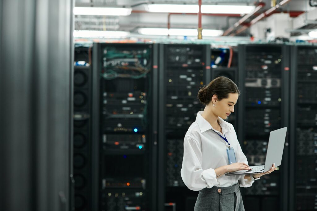 An IT specialist in a white shirt works diligently in a busy server room, handling technology.